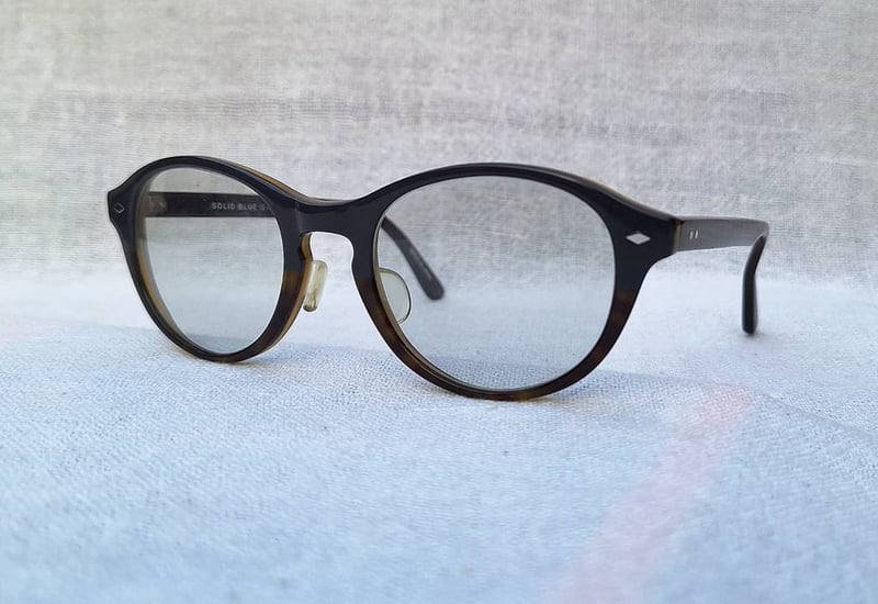 แว่นตาเวลลิงตัน–แฮนด์คราฟท์จากเมืองซาบาเอะ โซลิดบลู–SOLID BLUE รุ่น S–165 ตัวแท้ สภาพเทพ เก่าเก็บฤดูใบไม้ผลิ ค.ศ.2011 กรอบอะซีเทต–อนุพันธุ์เส้นใยฝ้าย–สีนาวีบลูสลับน้ำตาลกลาง เลนส์กระจกคริสตัลออโต้ฝรั่งเศส สีเทา–สว่าง ปรับความเข้มอัตโนมัติ ขนาดมาตรฐาน–Standard One Size 140mm สวมใส่ได้ทุกขนาดใบหน้า