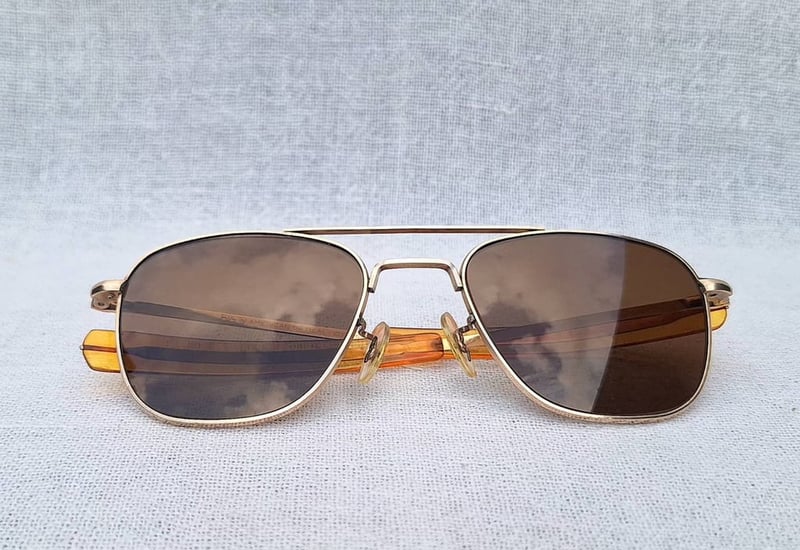 ราชันย์แห่งแว่นตาเสืออากาศยุคสงครามเวียดนาม เอโอ 12K GF–AO American Optical ตัวแท้ สภาพเทพ เก่าเก็บทศวรรษ 1960 กรอบทองคำแท้–หุ้ม 12K GF สัดส่วนทองคำบริสุทธิ์ 50% โคตรเลนส์กระจกคริสตัลพระเจ้าล้ำค่า CARL ZEISS JENA ที่ได้รับยกย่องว่าดีที่สุดตลอดกาลของชนชาติเยอรมัน ขนาดมาตรฐาน–Standard One Size 139mm